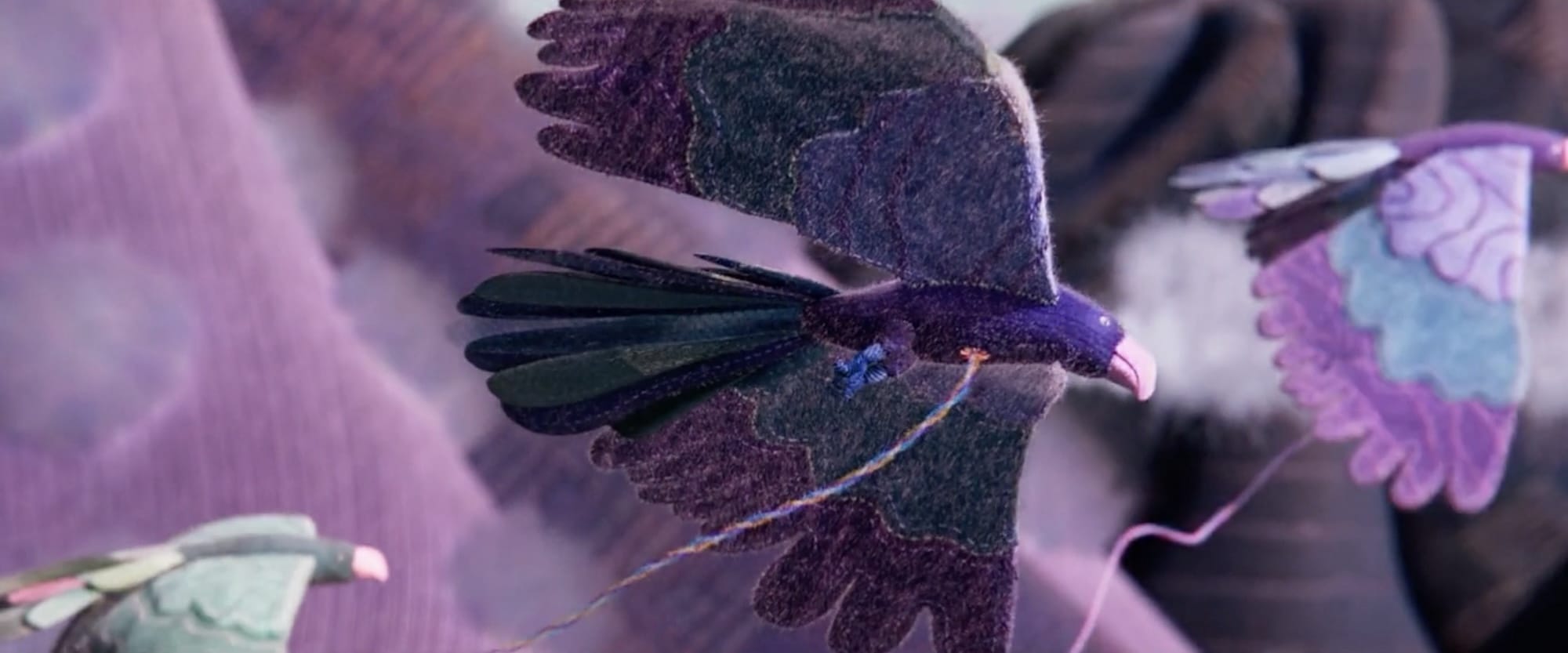 a still from an animated film called "Au 8ème Jour" showing birds flying in the air, tethered to colorful pieces of yarn
