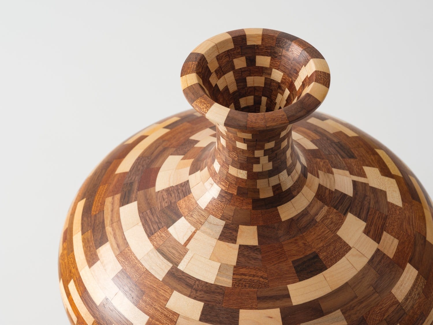a detail image of a wooden vessel made of stacked pieces in varied colors