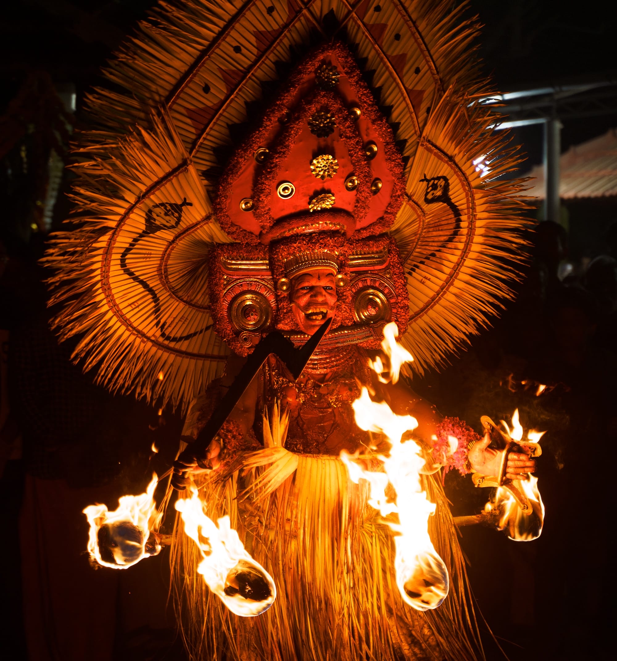 a photograph by Navneet Jayakumar of an elaborate ceremonial event around a fire, focused on an outfit worn by a performer for Theyyam, in Kerala, India