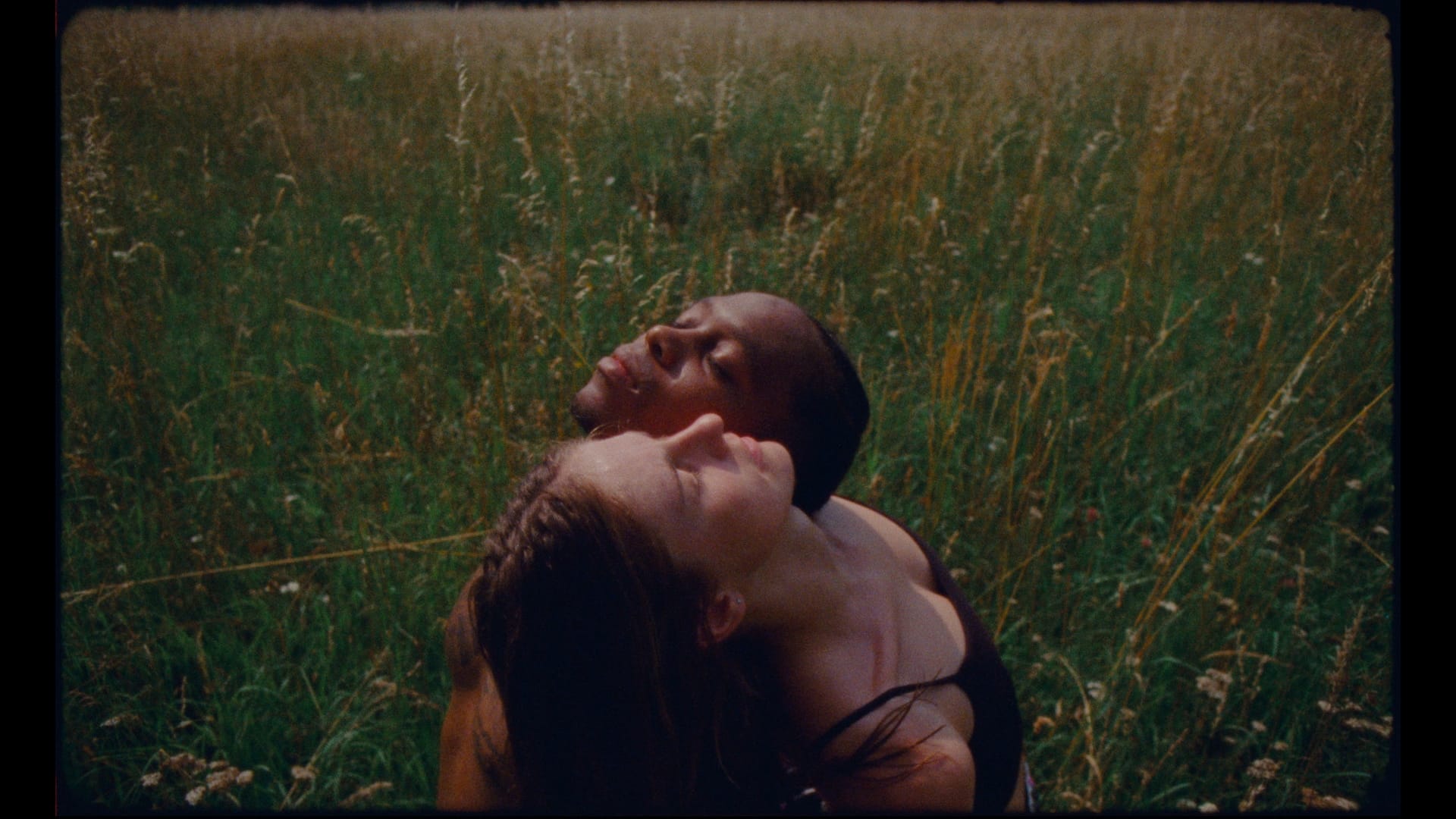 a still of two women with their backs together in a meadow