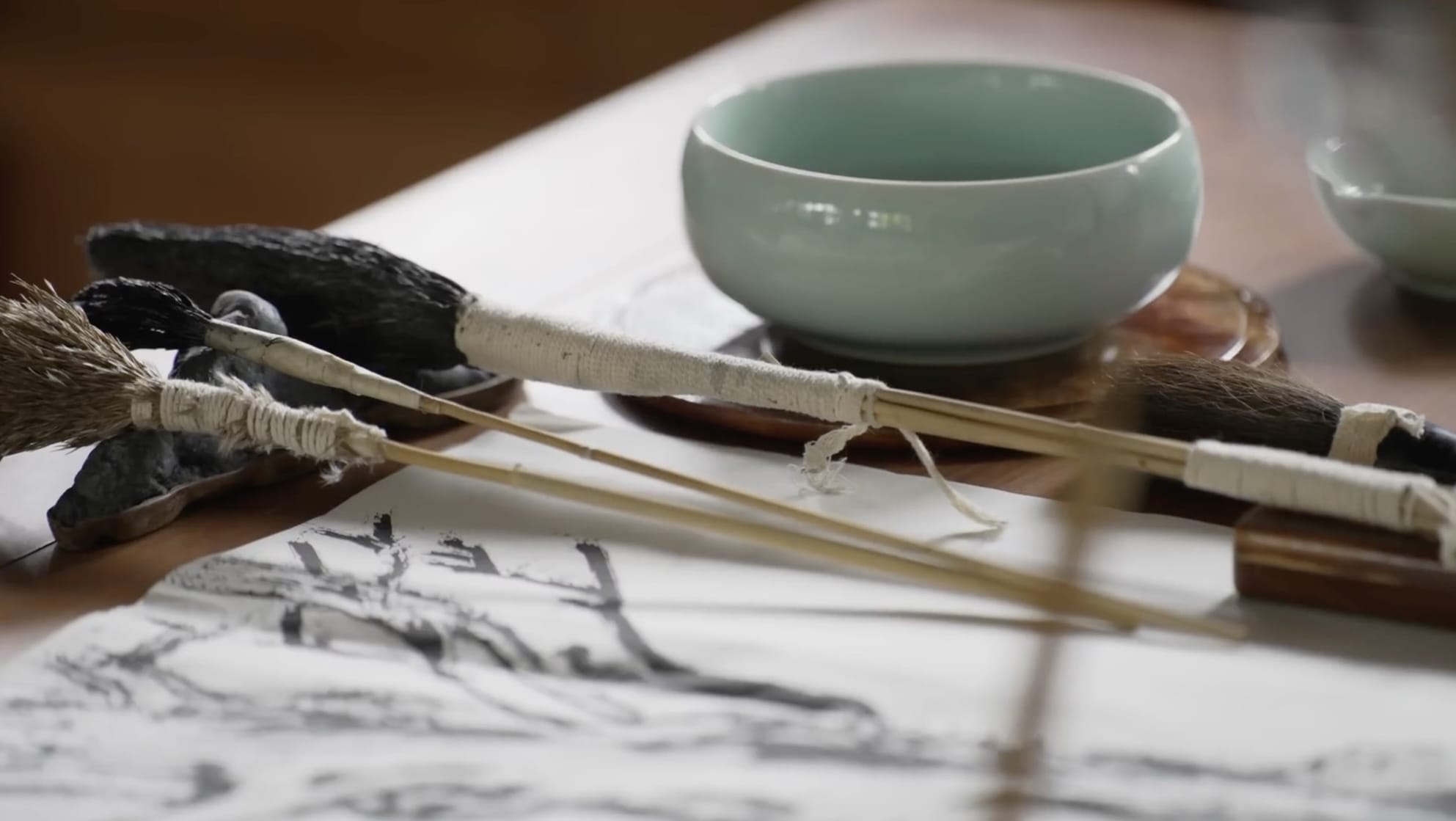 a still from a short documentary showing handmade brushes on a table with a bowl