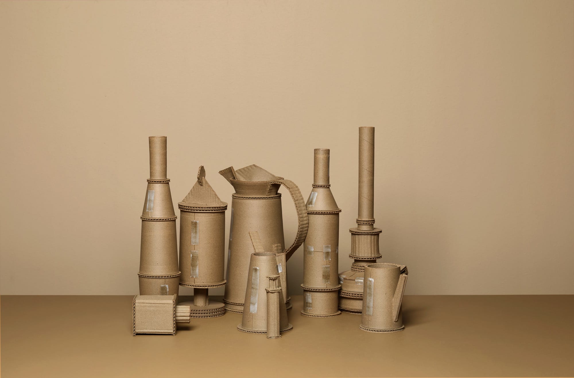 a series of ceramic vessels by Jacques Monneraud that resemble cardboard with tape, arranged to mimic a painting by Giorgio Morandi