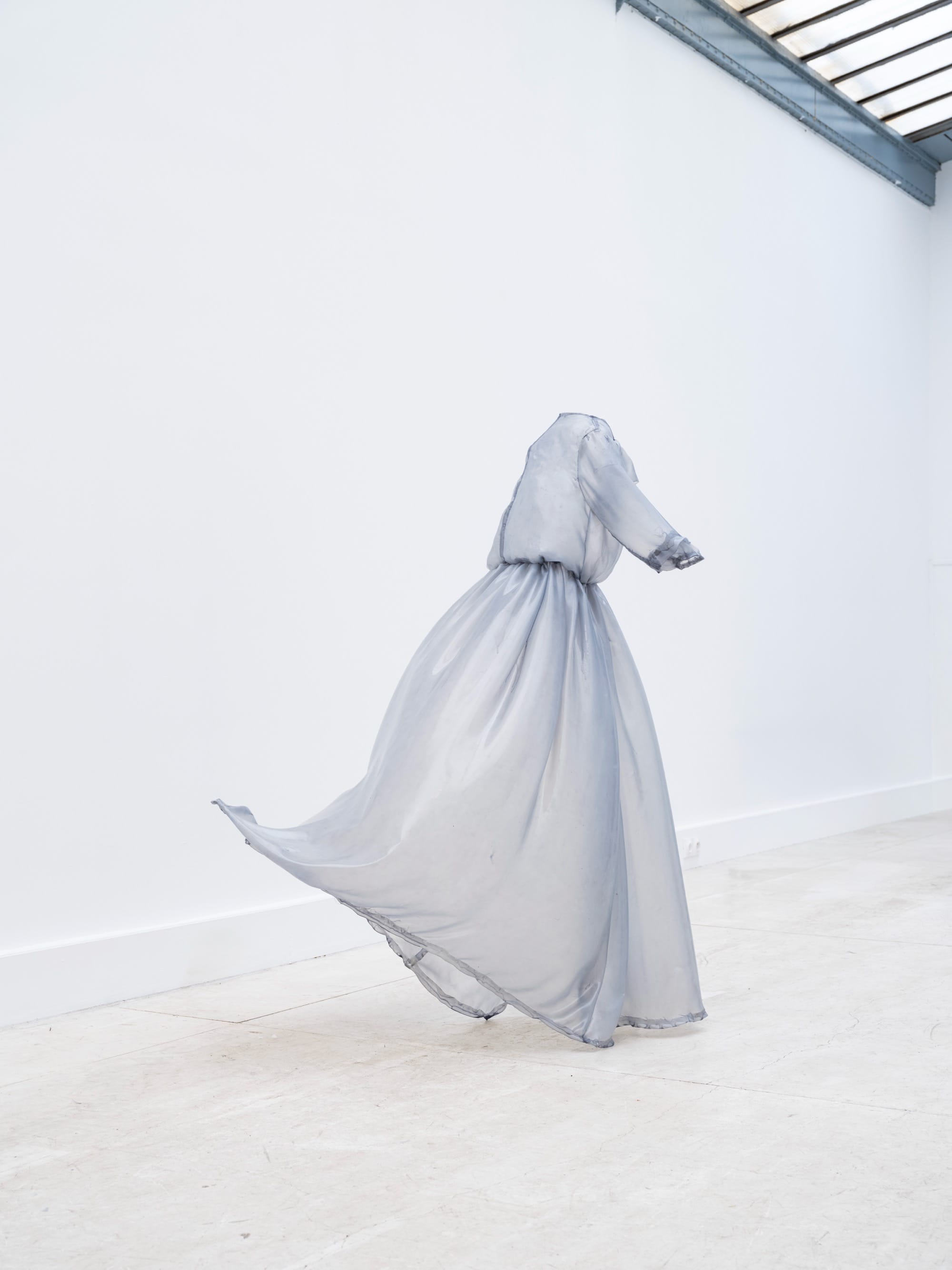 A stiff pale blue fiberglass victorian style dress by Brandon Morris that stand without wearers in the middle of a gallery