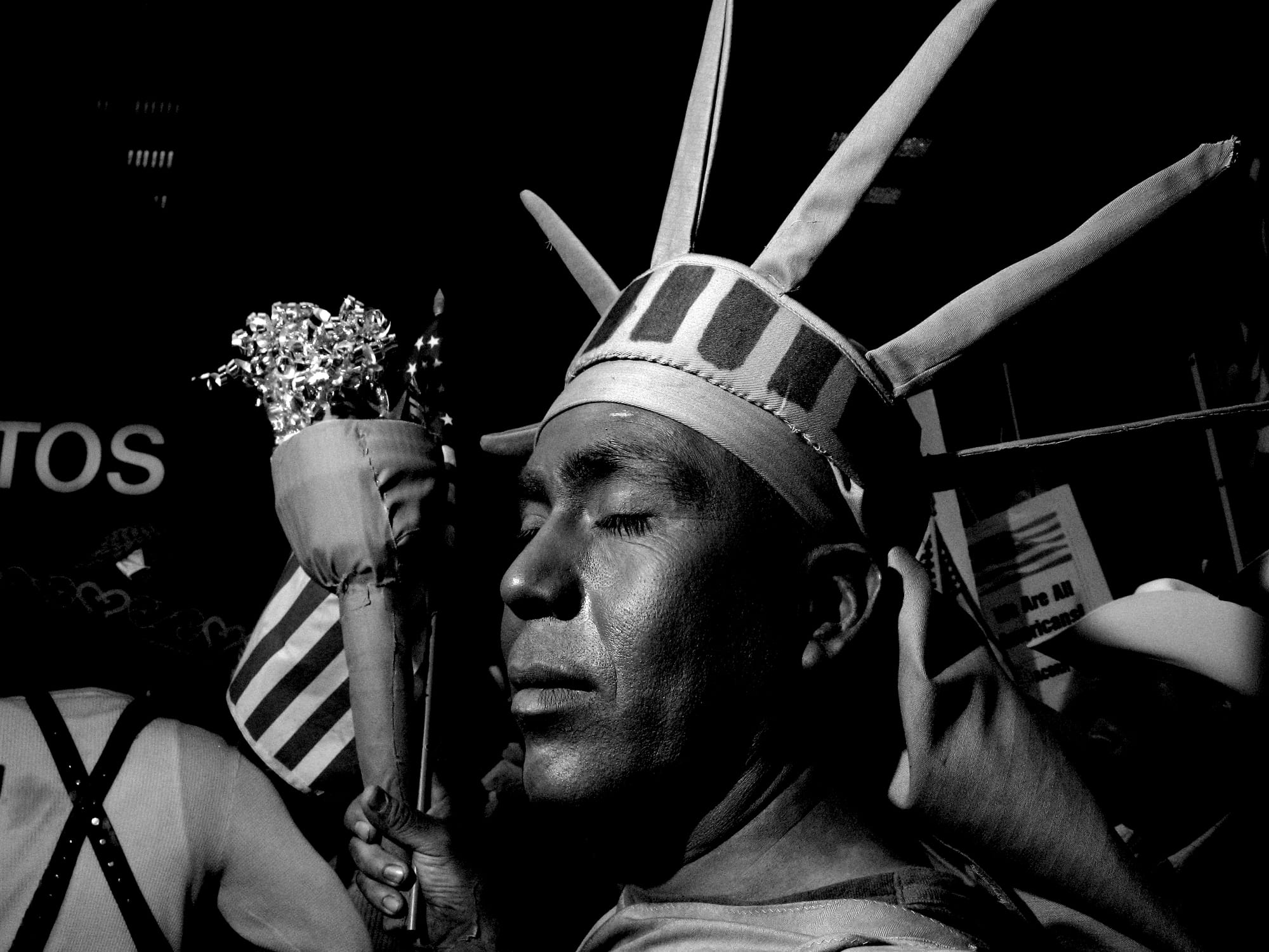 A black-and-white photograph by Carlos Javier Ortiz of protestors in Chicago, with a central figure dressed like the Statue of Liberty