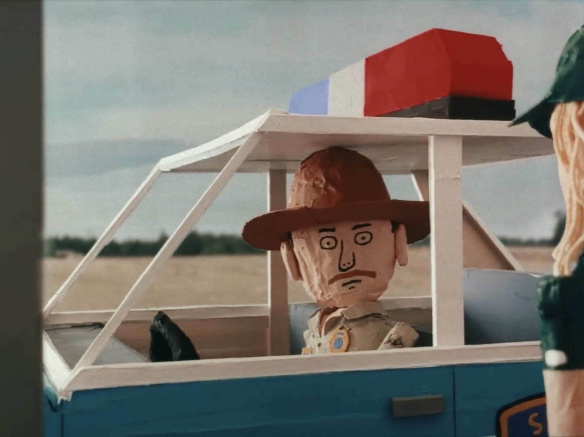 a still from a stop-motion animated video of a sheriff in his car
