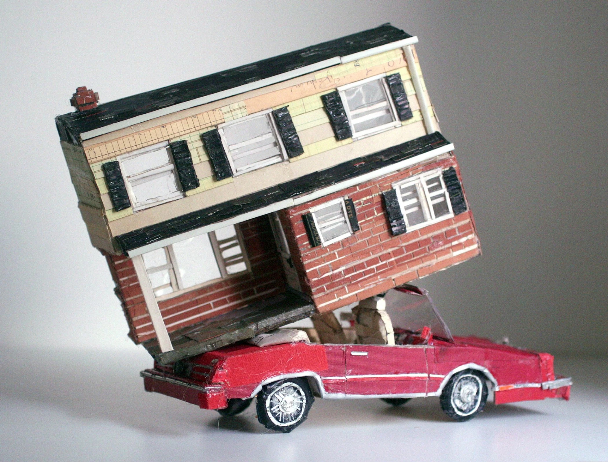 a red car hauling a house made from found scraps by Lydia Ricci