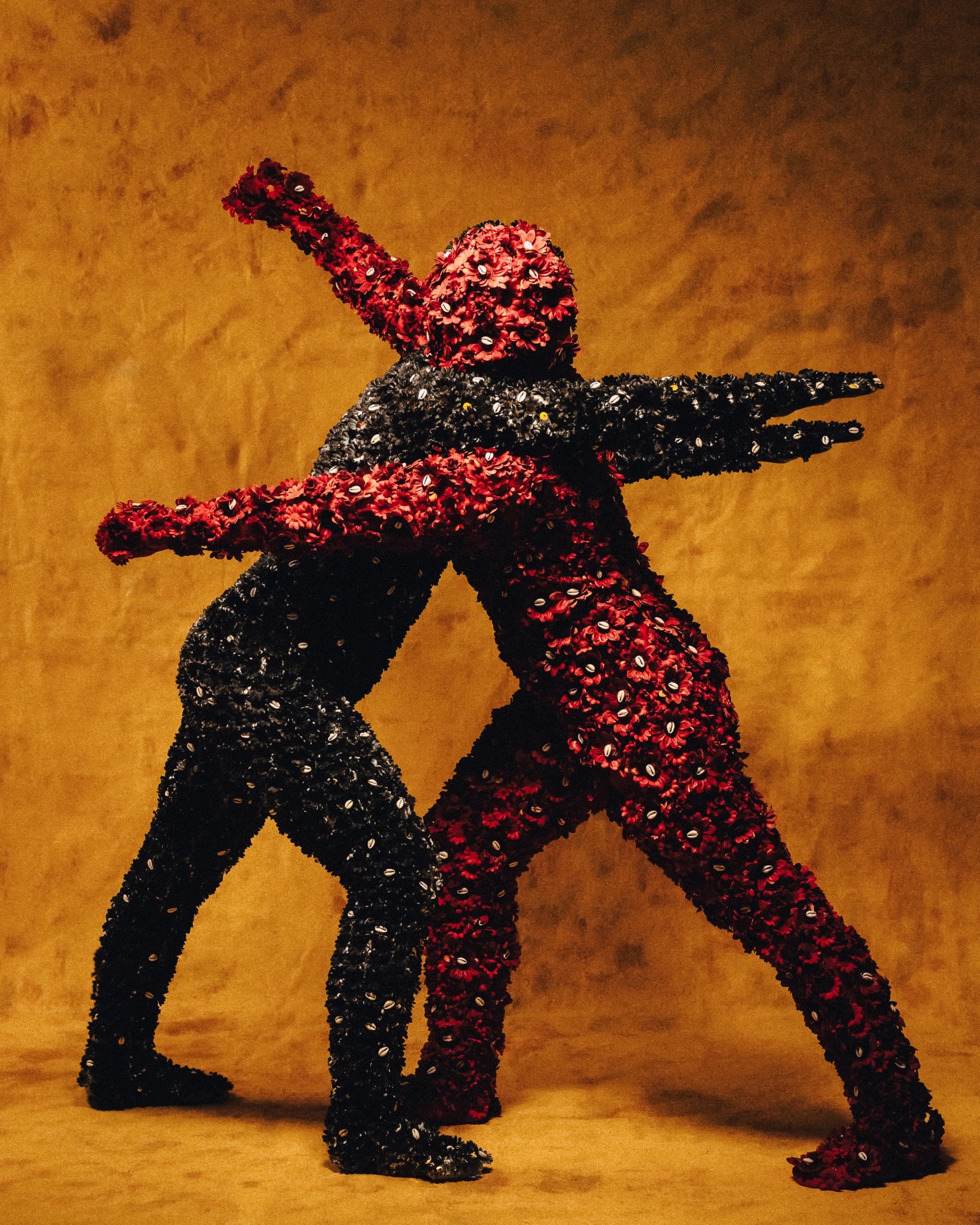 two embracing costumed figures with all-over outfits of fabric flowers