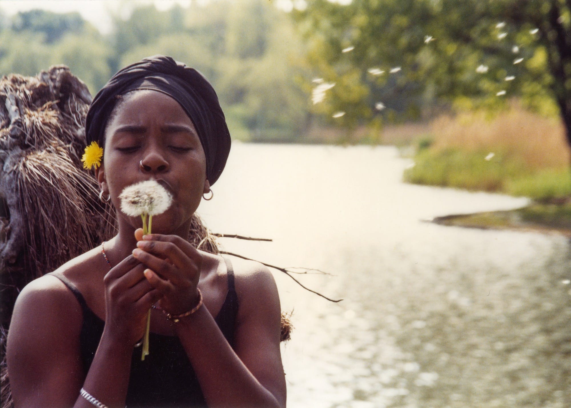 a photo by Jamel Shabazz of a girl blowing a dandelion
