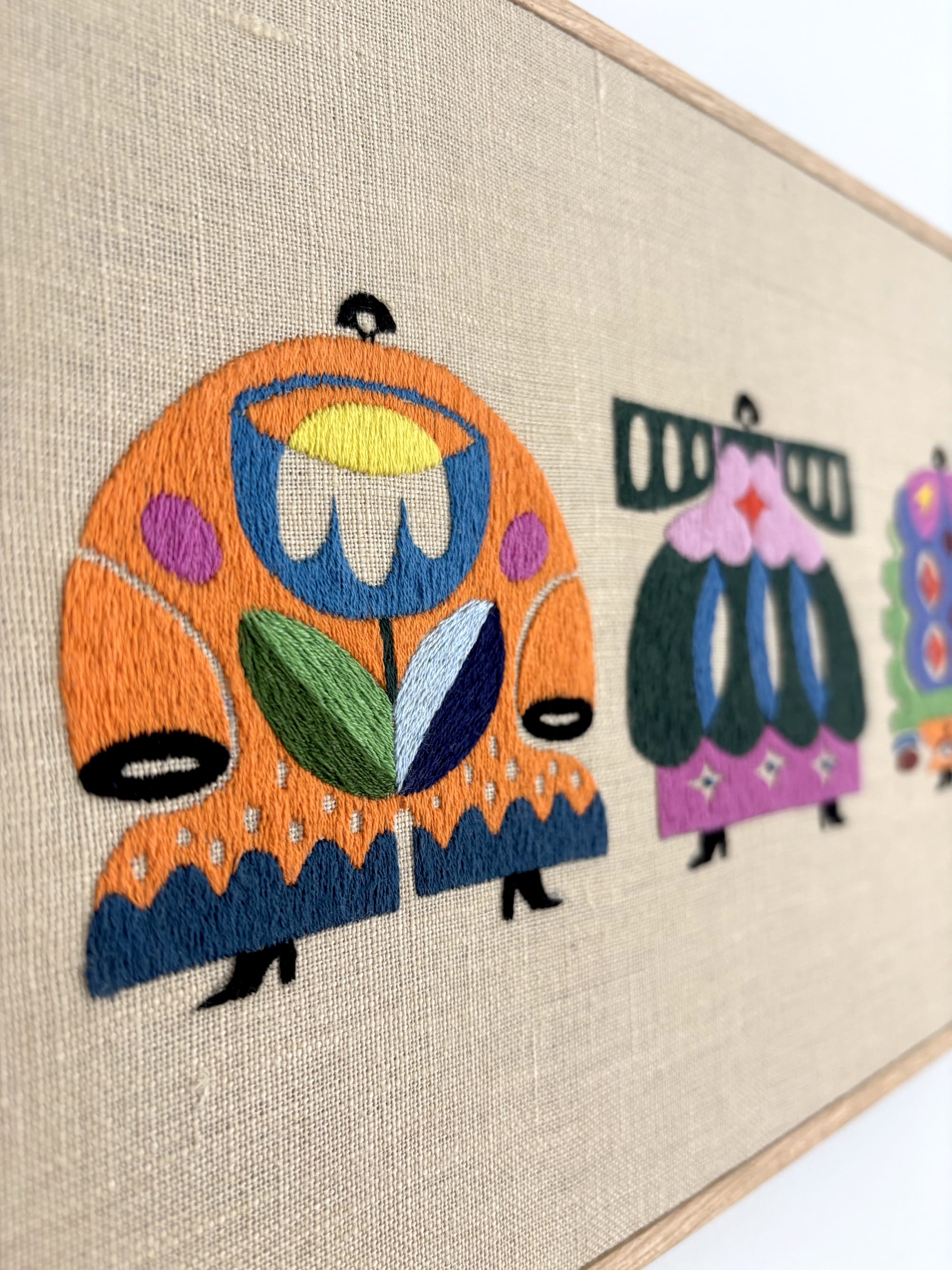 a detail of an embroidered artwork by Irene Saputra of four colorful, patterned, symmetrical, abstractly shaped figures