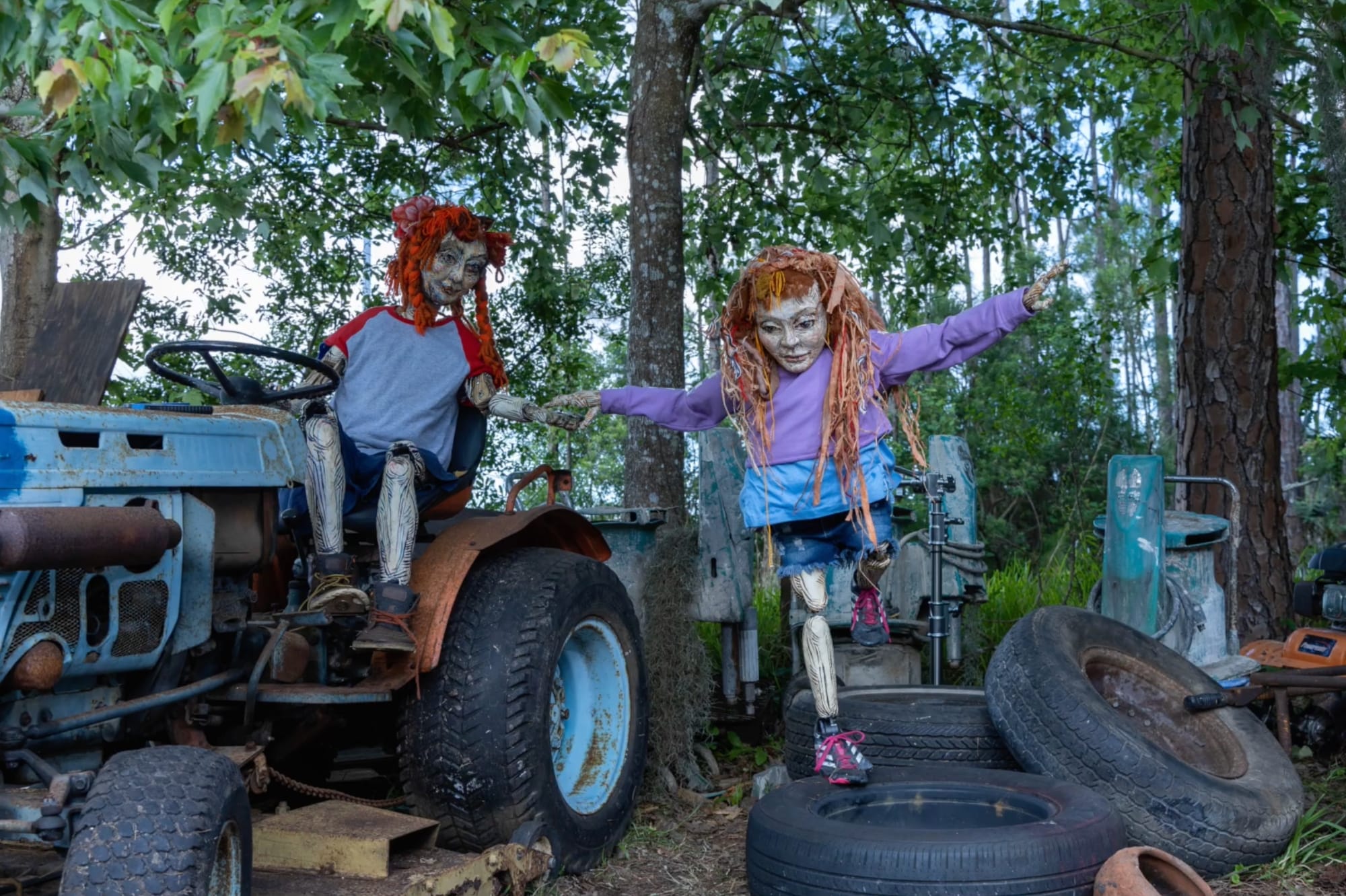a still of two stop motion figures, one on a tractor, the other climbing on tires, in a film by Swoon