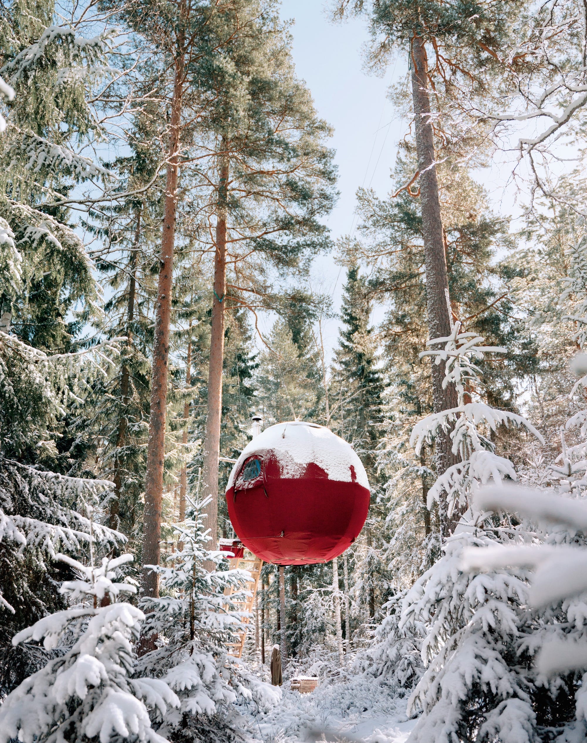 a red modern treehouse in a snow-covered forest