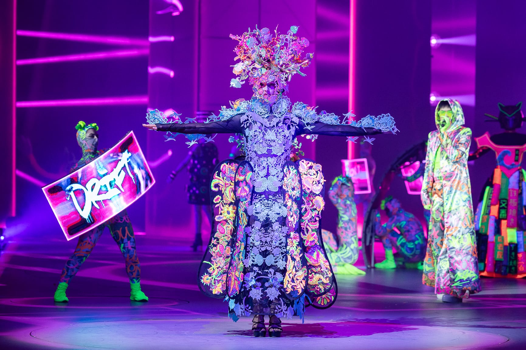 an elaborate costume worn by a performer on stage, glowing under black light