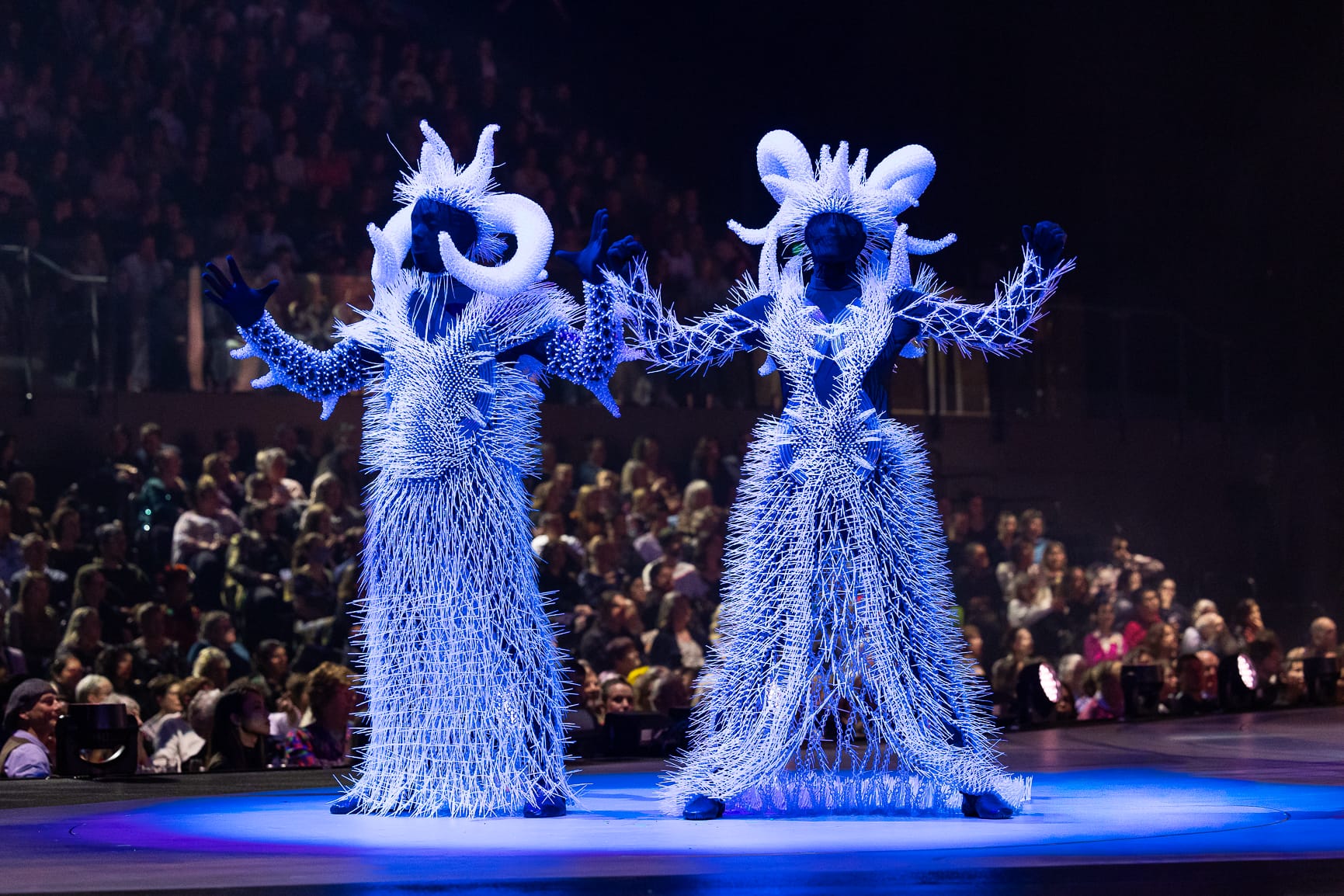 two glowing, blue, elaborate costume worn by performers on stage