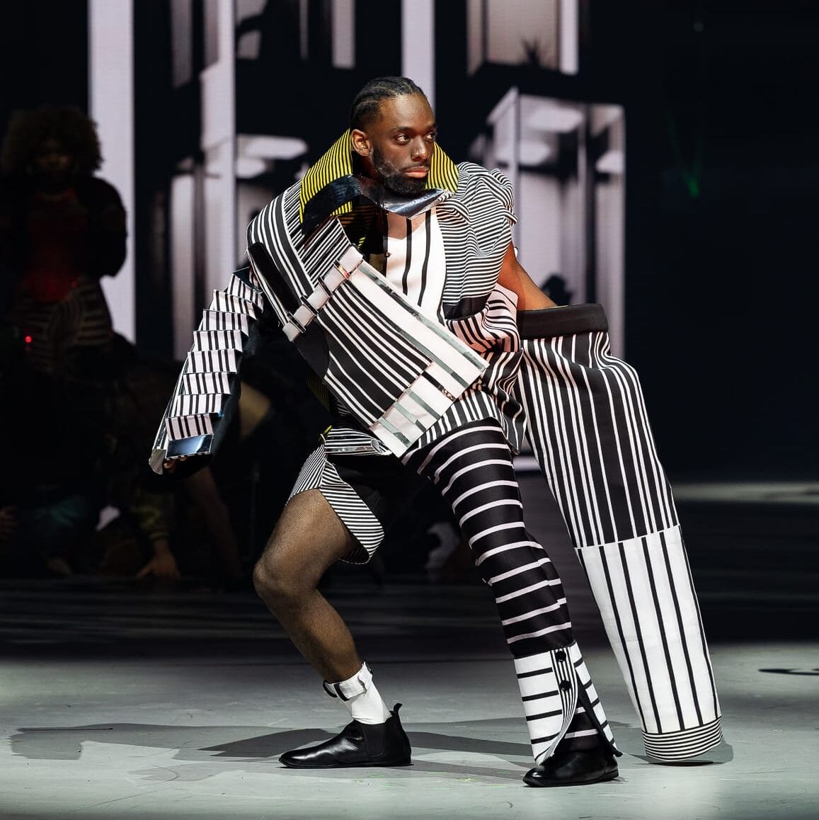 an elaborate costume in geometric black-and-white forms, worn by a performer on stage